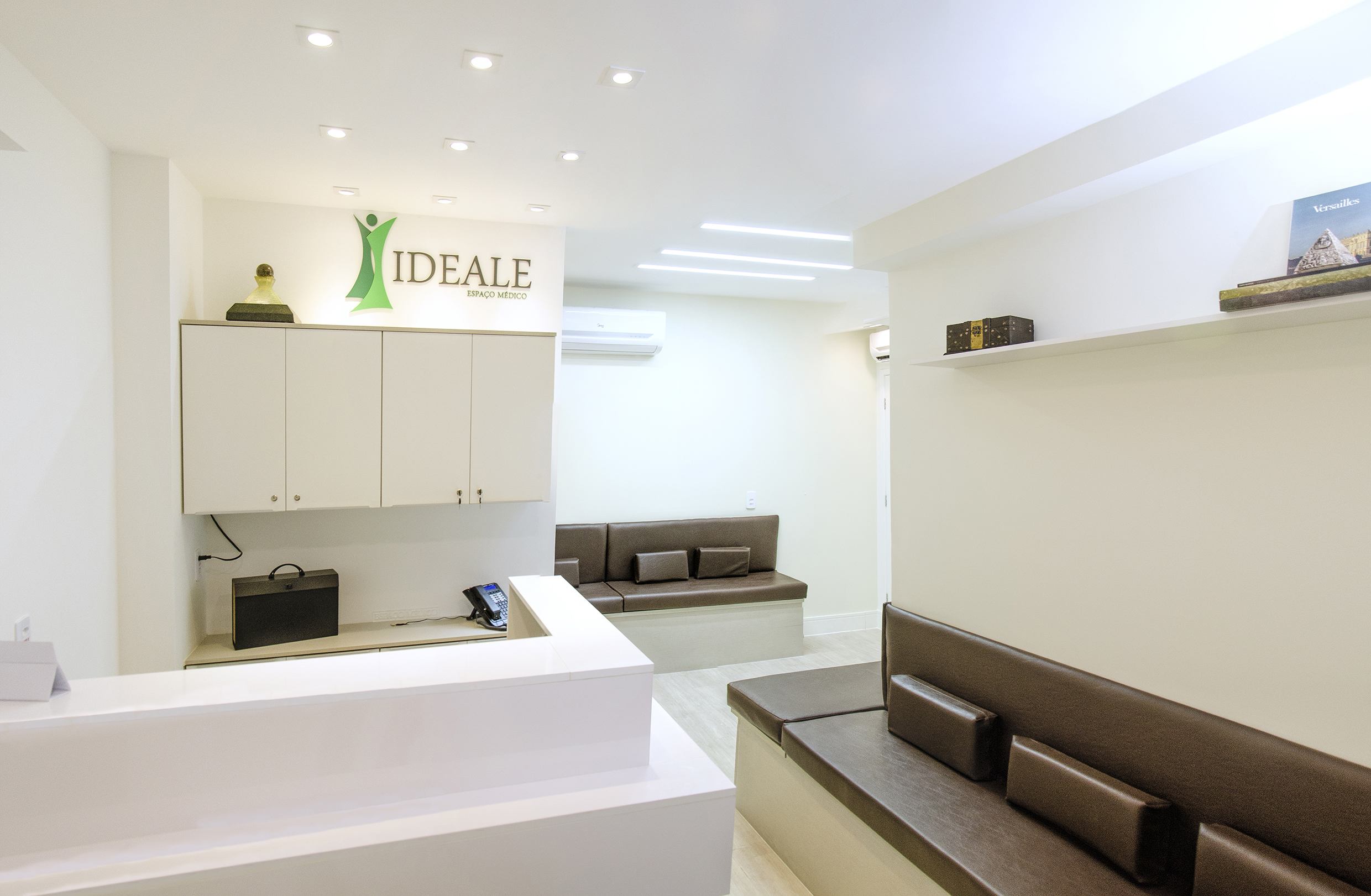 Recepção do Ideale Espaço Médico com balcão branco e logo na parede